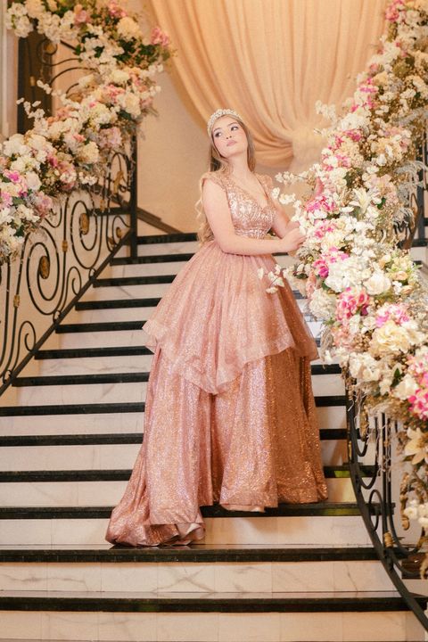 Woman wearing an elegant pink formal gown on a staircase