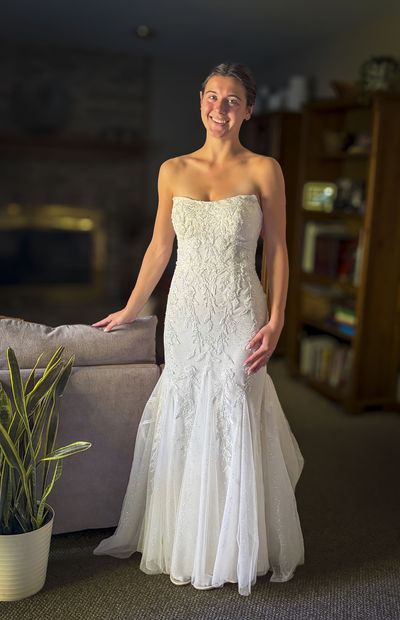 Client wearing a fitted strapless lace wedding dress, front view