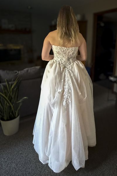 Back view of an embroidered wedding dress with a gathered bustle